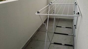 A balcony with a white metal drying rack.