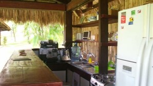 A compact kitchen with a wooden counter, a stove, a sink, and a refrigerator. - Pousada Point Break (Caucaia)