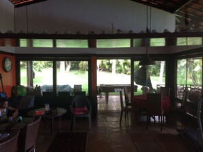 Zona interior àmplia amb vista a un jardí, que inclou una taula de menjador, cadires i un ventilador.