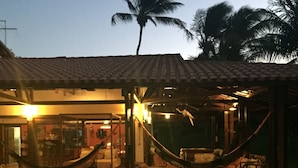 A house with a tiled roof, a hammock, and a porch. - Pousada Point Break (Caucaia)