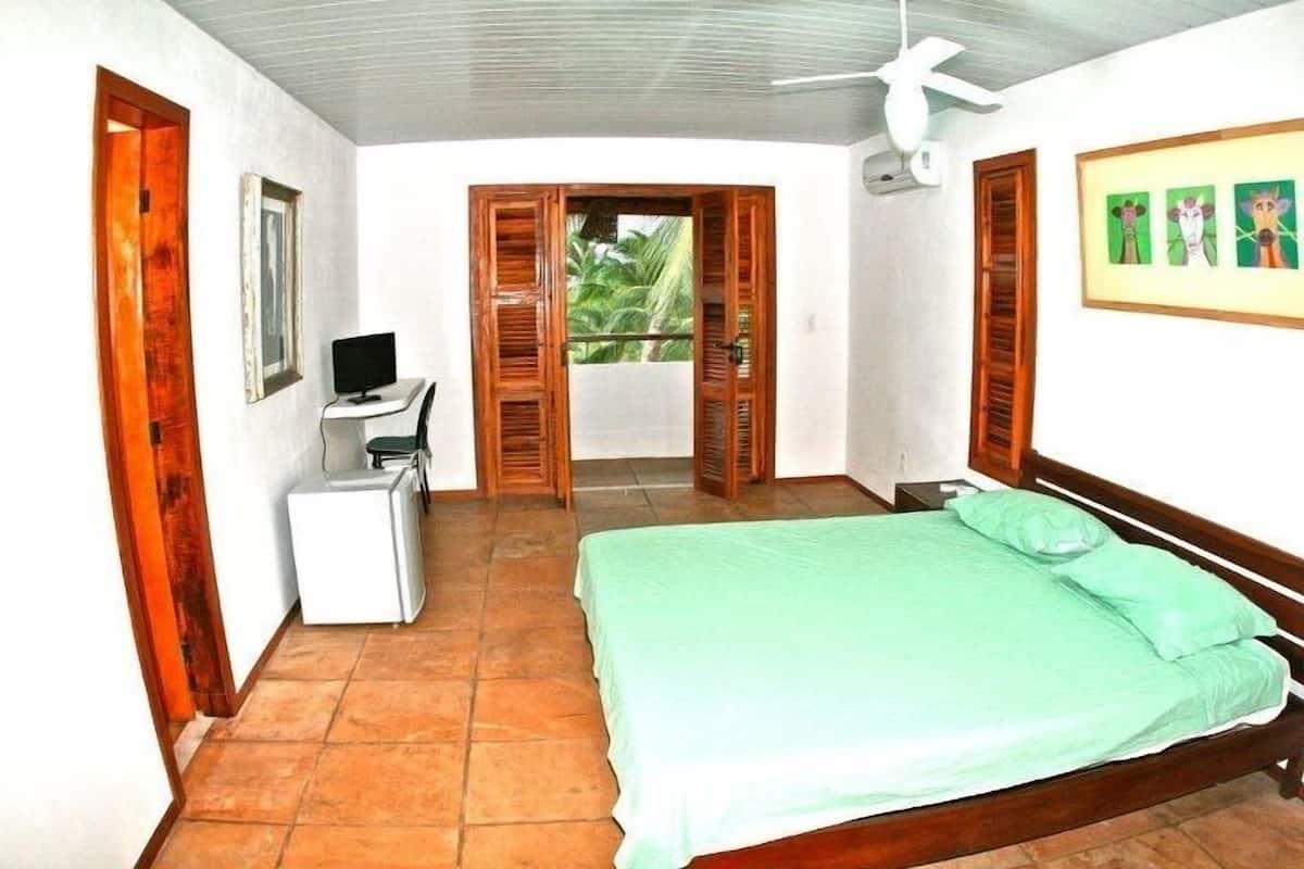 Une chambre à coucher comprenant un lit, un bureau, une chaise, un téléviseur et une fenêtre avec des volets.