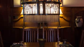 A dining area with a wooden table set for a meal, a hanging light fixture, and artwork on the walls.