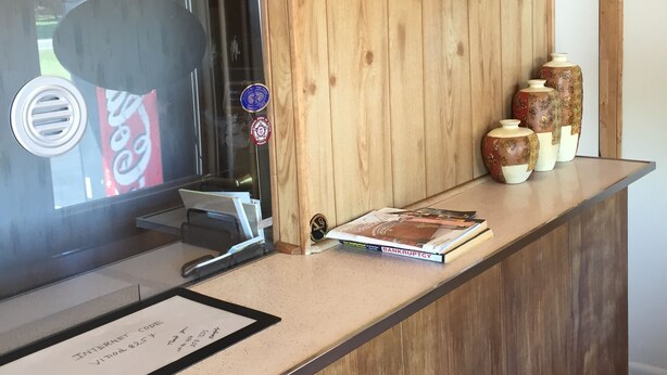 Uma mesa de recepção de madeira com uma placa de registro, um mapa e vasos decorativos.