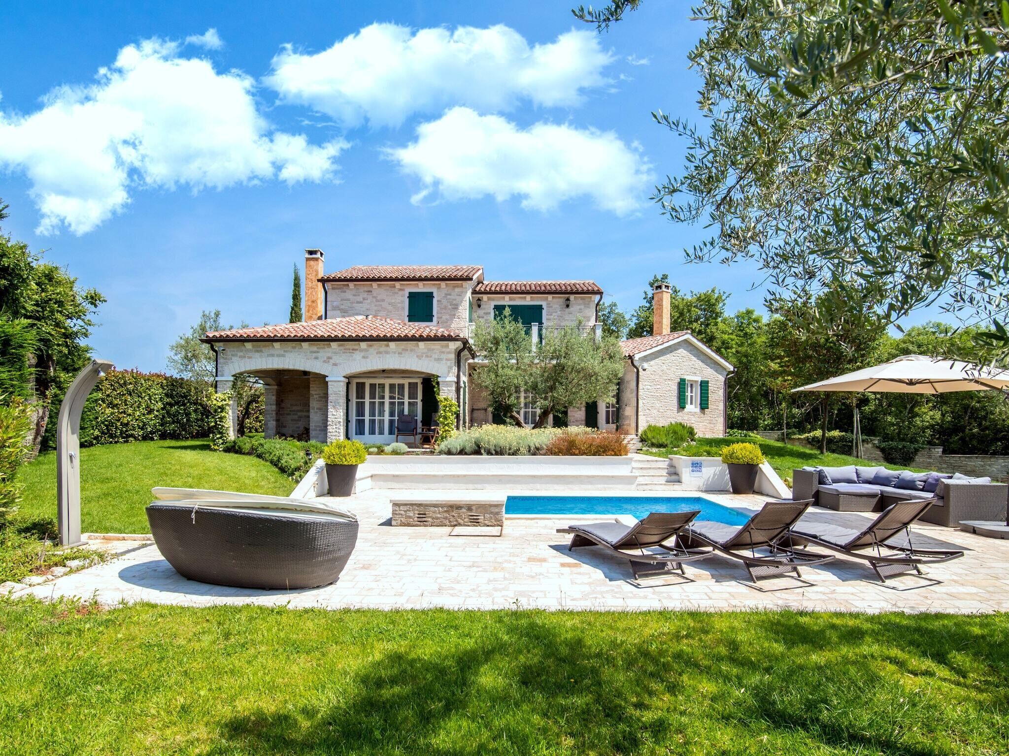 Una casa de piedra de dos pisos con piscina, mobiliario exterior y un jardín bien cuidado.