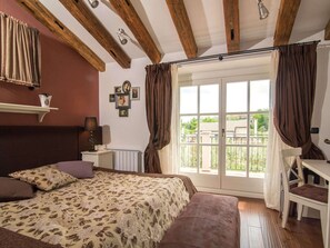 Une chambre à coucher comprenant un lit, un bureau, une chaise, un radiateur et une fenêtre avec des rideaux.