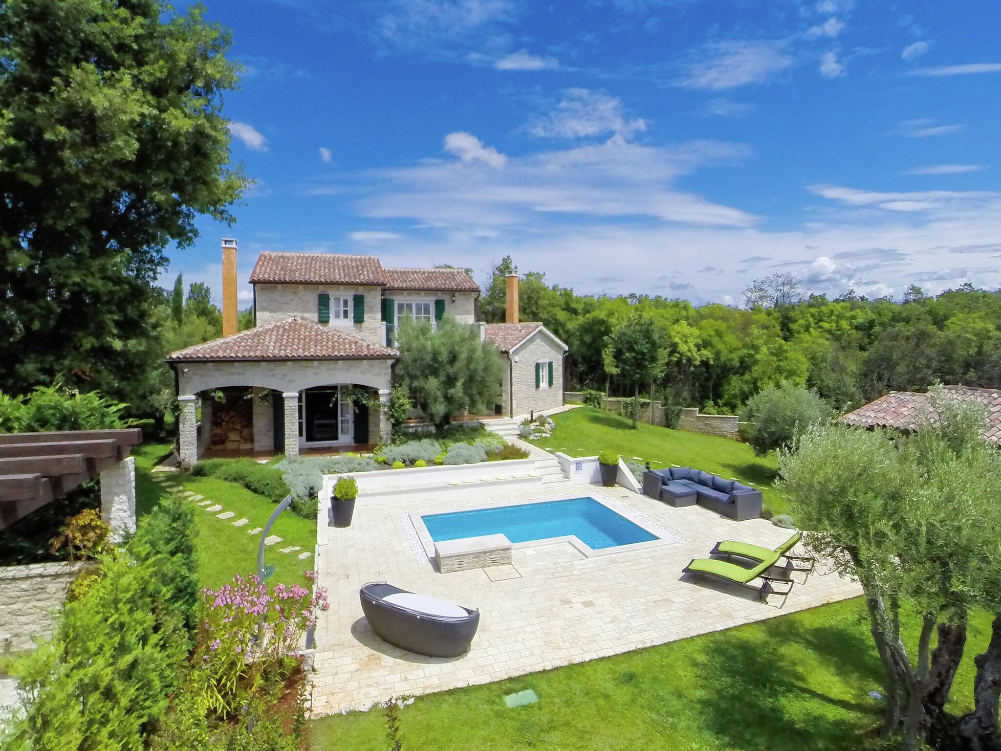 Una casa in pietra su due piani con piscina, area salotto esterna e giardino curato.