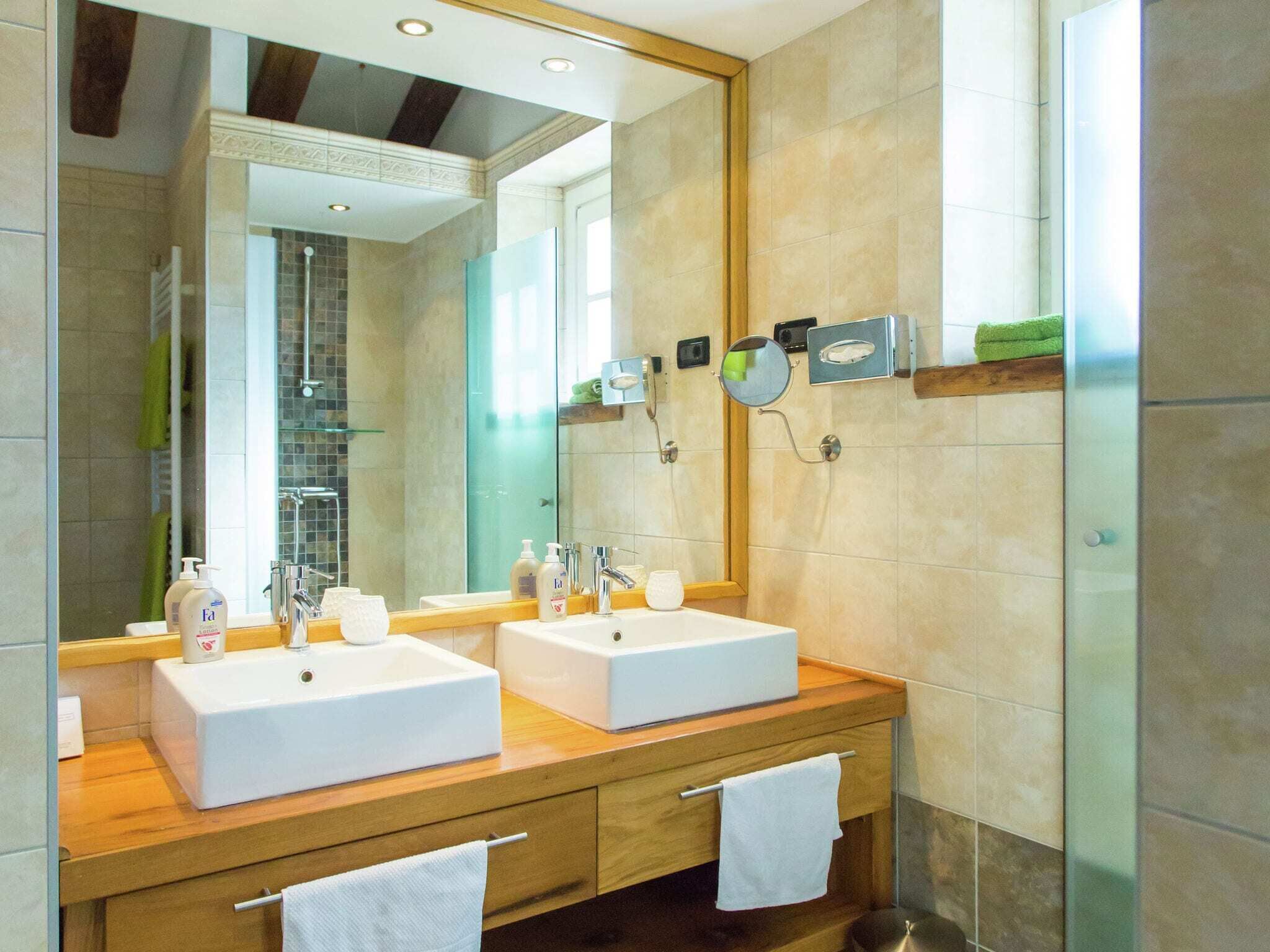 Un baño moderno con dos lavamanos, un espejo grande y una ducha.