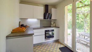 A compact kitchen with white cabinets, a built-in oven, and a large sliding glass door leading to an outdoor area.