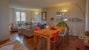 A living room with a wooden dining table, red chairs, a sofa, and a fireplace.