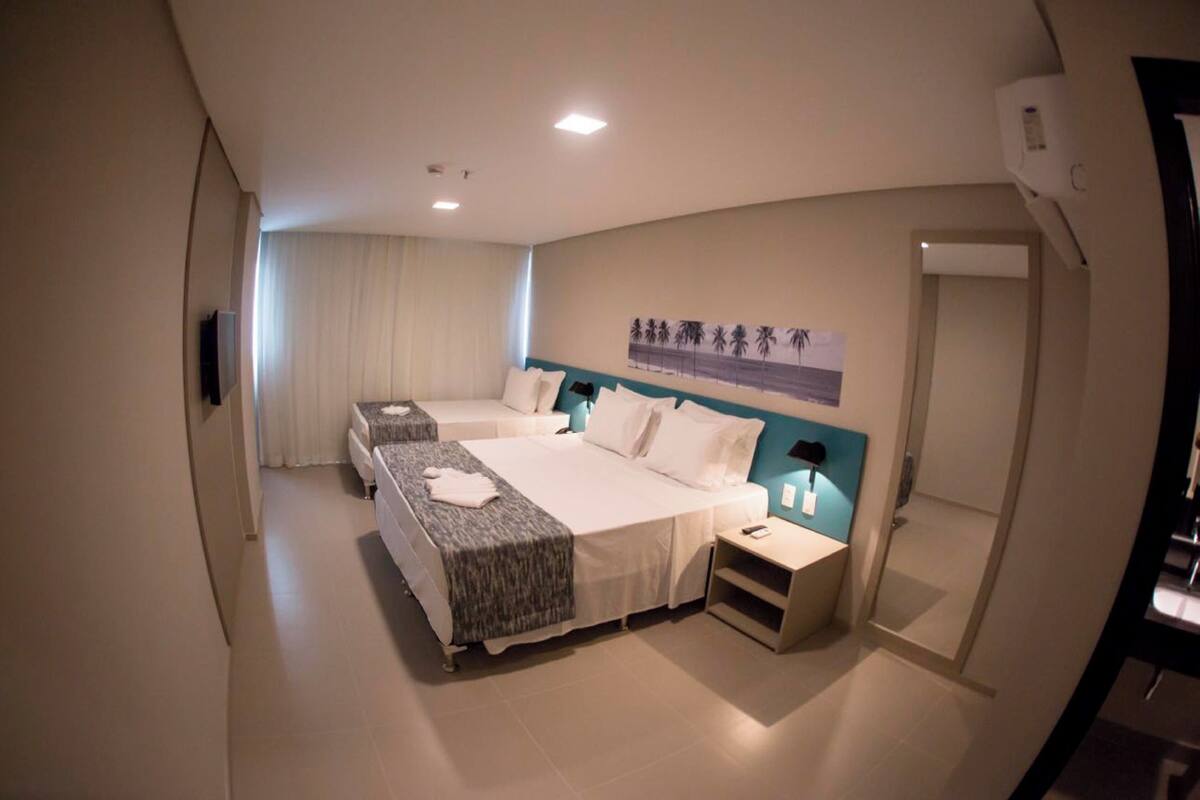Une chambre d’hôtel avec deux lits, un téléviseur à écran plat, une table de chevet et un tableau au mur.