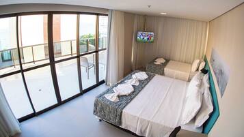 A hotel room with two beds, a large window, and a TV on the wall.
