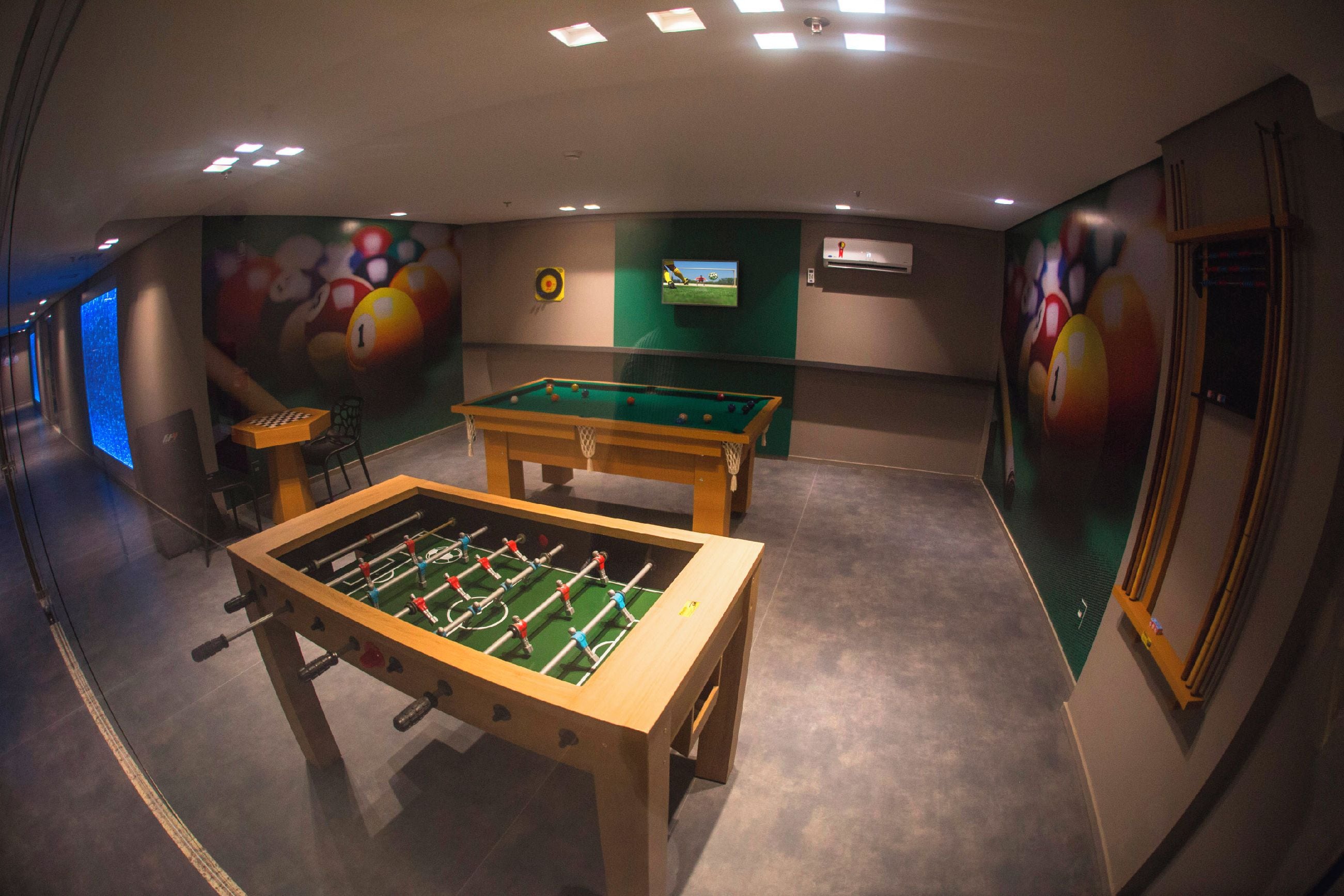 A billiards room with two foosball tables and a television screen.
