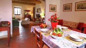 A dining area with a table set for four, surrounded by chairs, a sofa, and a fireplace.