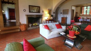 A spacious living room with a fireplace, two sofas, a dining area, and a large mirror.