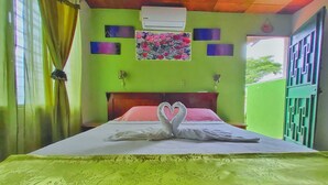 Een hotelkamer met een bed, groene wanden, een bloemkunstwerk en een hartvormige decoratie op het bed.