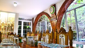 Een restaurant met een lange houten tafel, stoelen en een bakstenen muur met een klok.