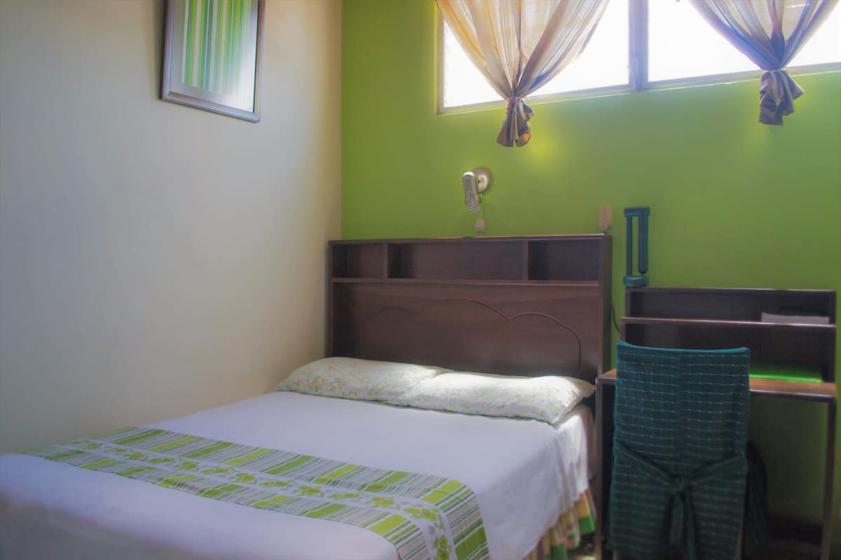 Una habitación con una cama, un escritorio y una silla.