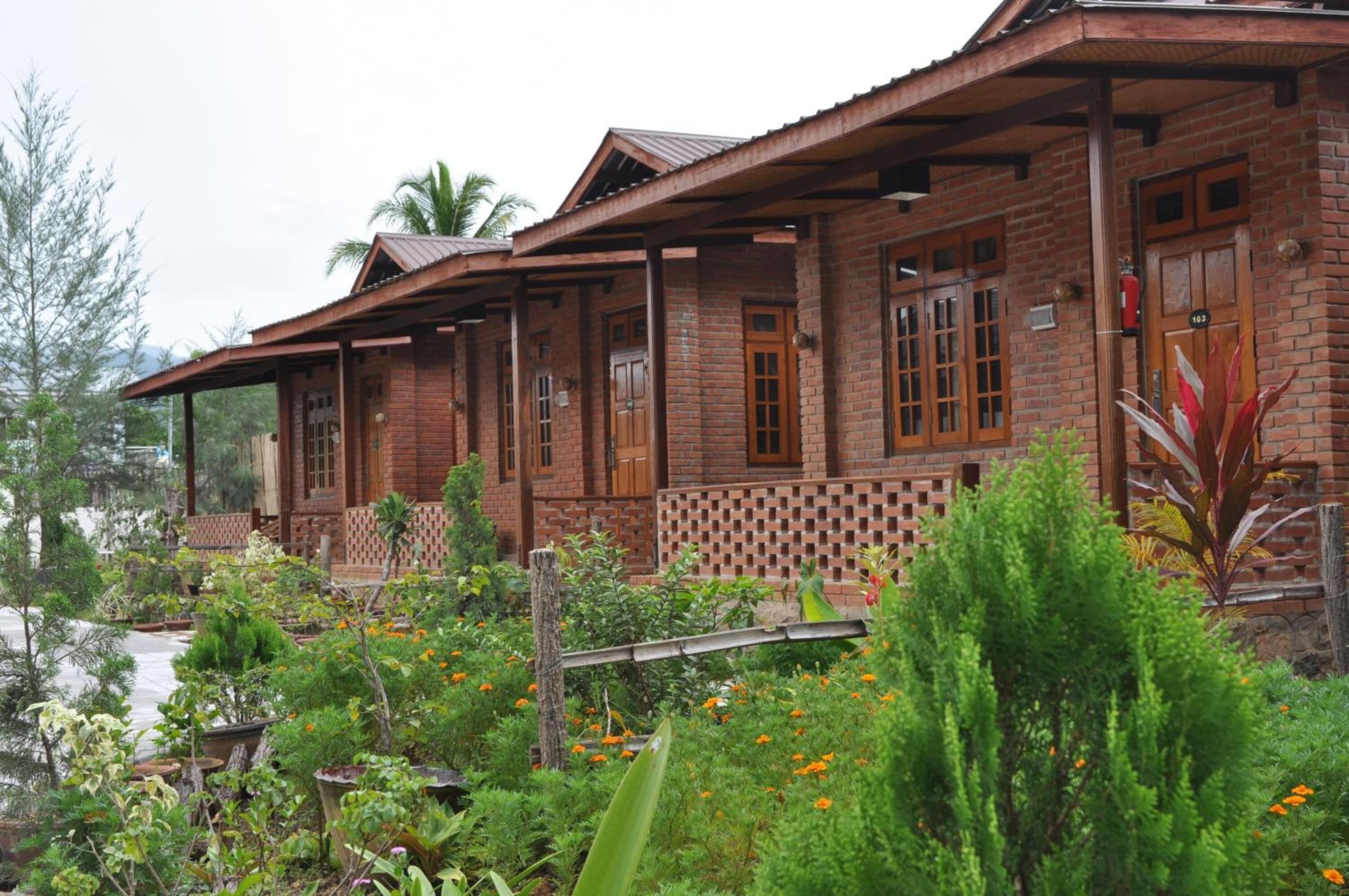Une maison rustique en bois, avec une façade en briques, de nombreuses fenêtres et un porche abrité.