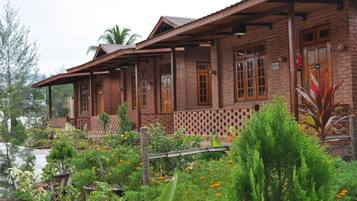 Une maison rustique en bois, avec une façade en briques, de nombreuses fenêtres et un porche abrité.