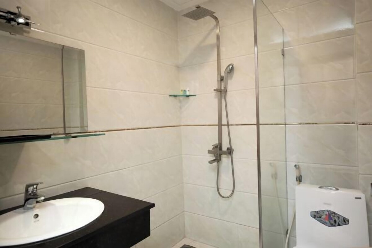 Een badkamer met een witte wastafel, een douchecabine van glas en een wit toilet.