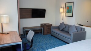 A hotel room with a bed, a desk, a chair, a sofa, a TV, a lamp, a picture on the wall, and a small wooden cabinet. - Holiday Inn Express & Suites Ciudad Obregon by IHG (Cajeme)