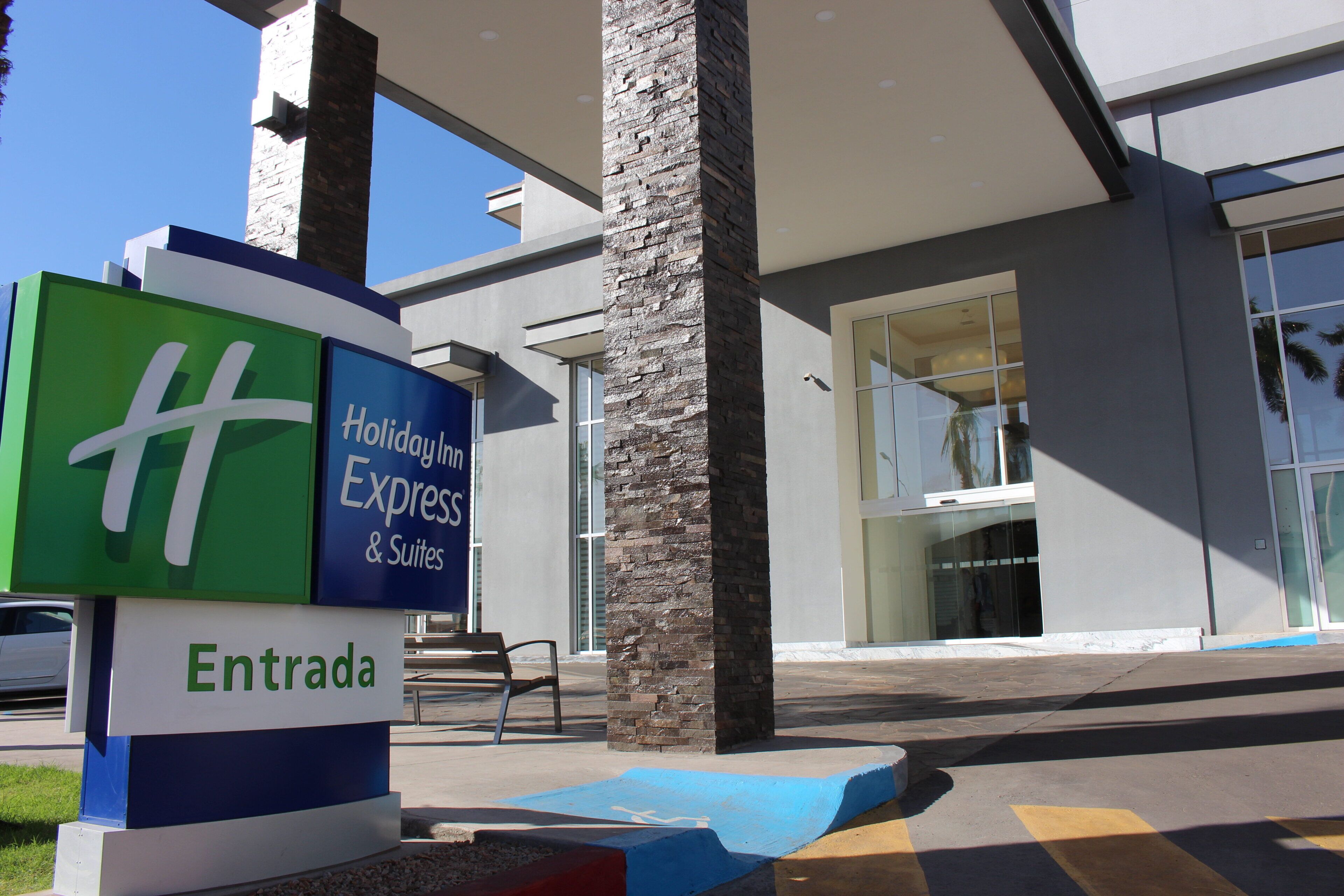 Entrada de hotel com placa da Holiday Inn Express & Suites e sinalização de 'Entrada'.