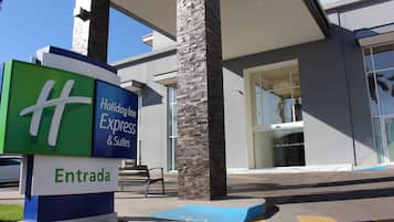Entrada de hotel com placa da Holiday Inn Express & Suites e sinalização de 'Entrada'.