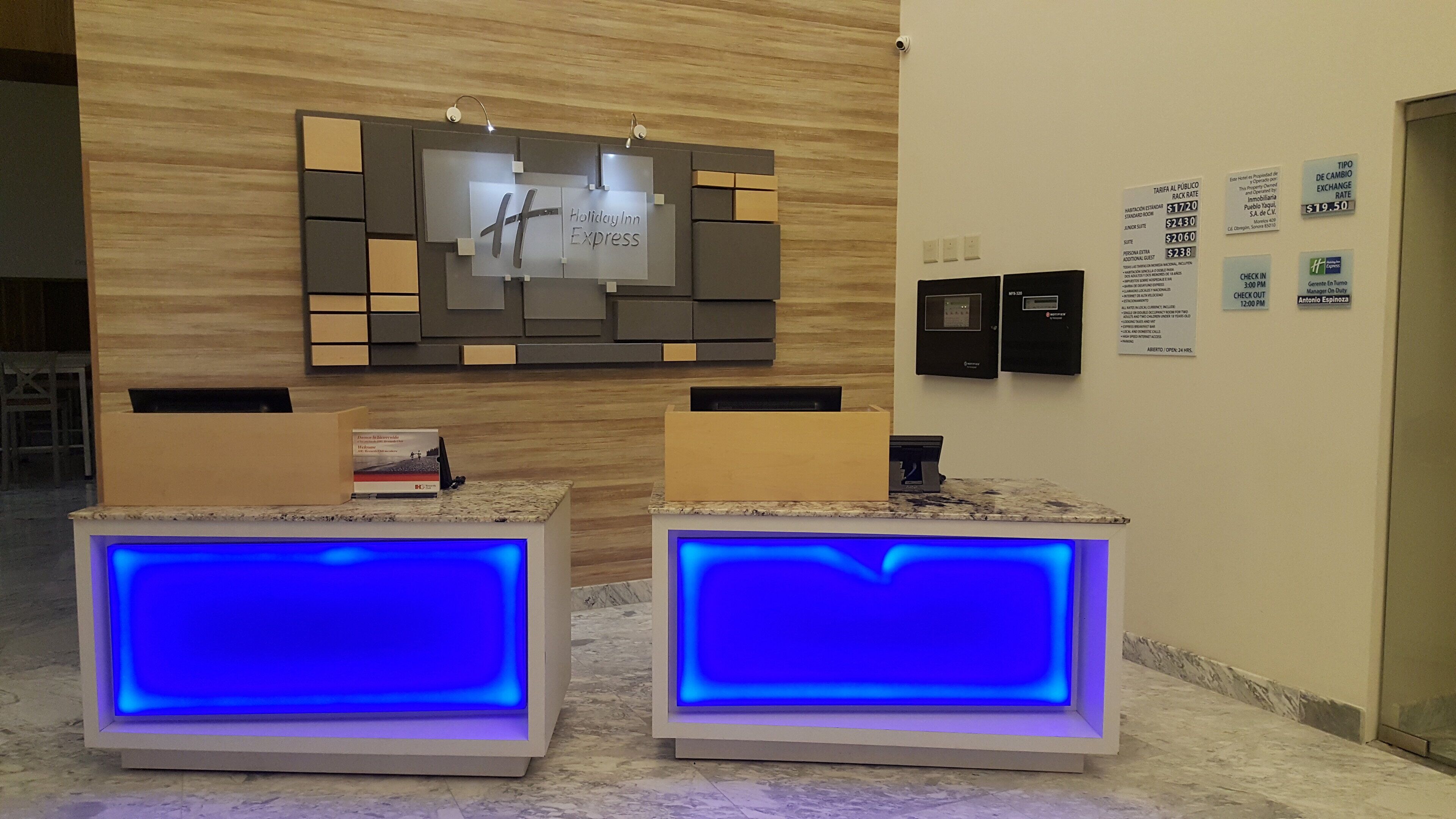 A reception area with a Holiday Inn Express sign, a check-in counter, and a digital display.