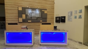 Un espace d’accueil avec une enseigne Holiday Inn Express, un comptoir d’enregistrement et un écran numérique.