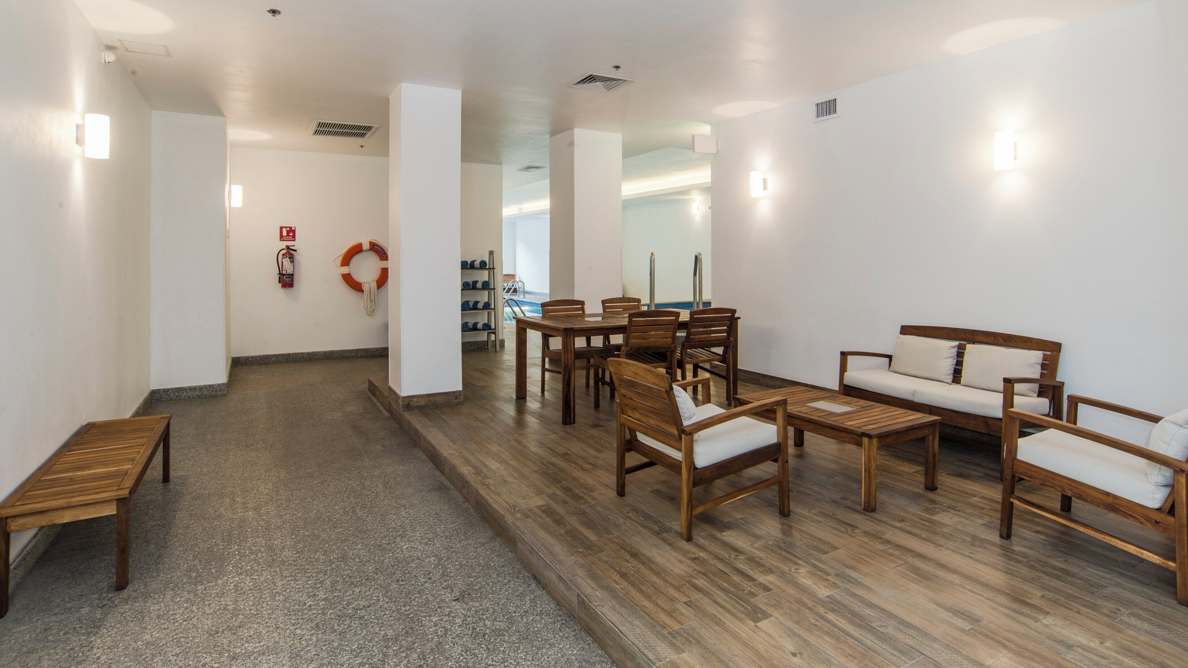 A hotel lobby with a reception desk, seating area, and a fire extinguisher.