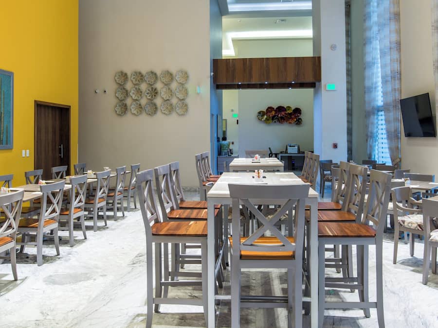 A dining area with multiple tables and chairs, a yellow wall with artwork, and a modern interior design.