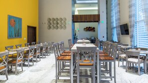 Un comedor con varias mesas y sillas, una pared amarilla con obras de arte y un diseño de interiores moderno.