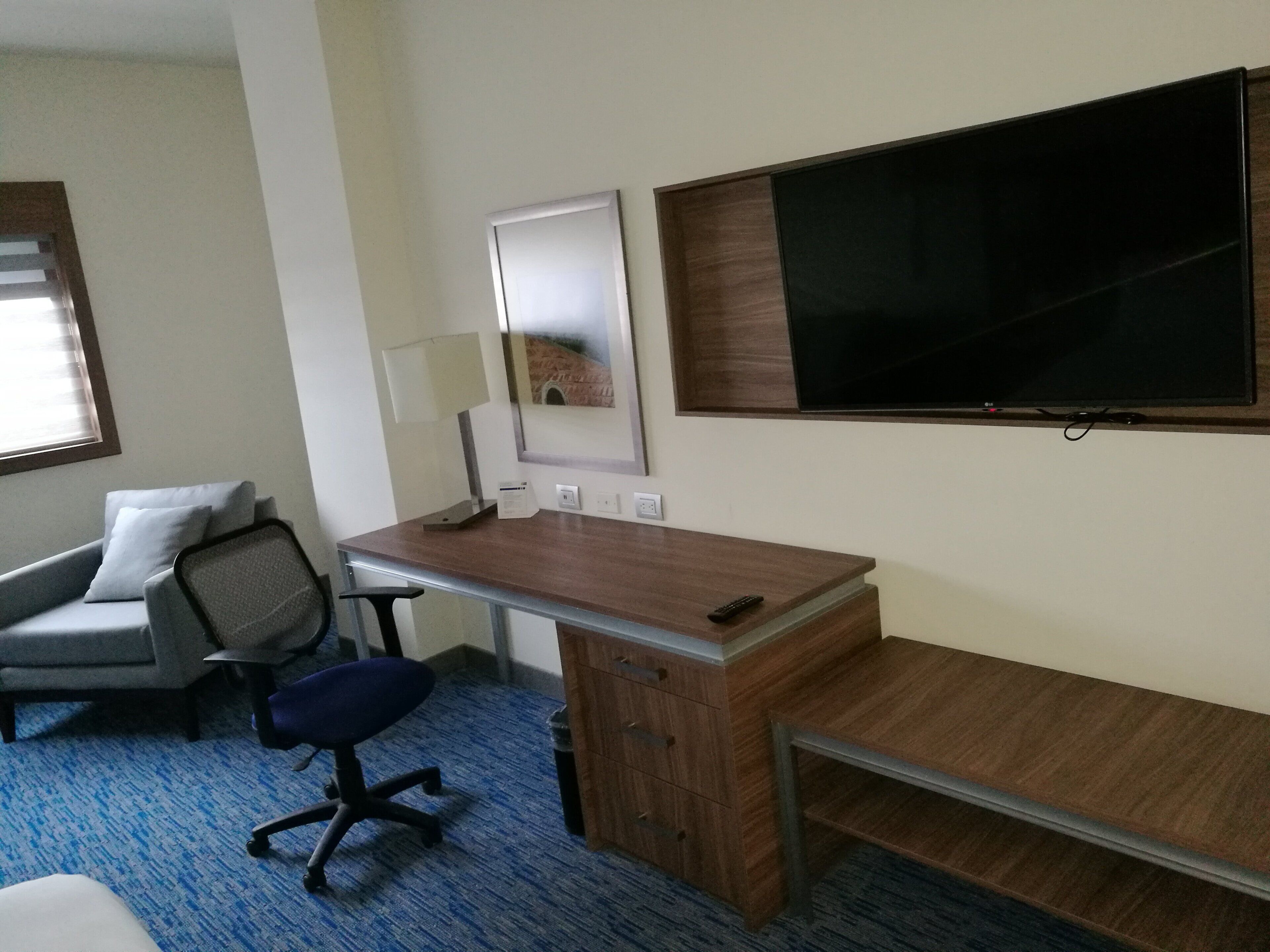 Una habitación de hotel con escritorio, silla y un ventanal grande.