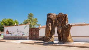 A sculpture of a tree trunk with a carved figure, a mural with birds and flowers, and a clear blue sky. - Holiday Inn Express & Suites Ciudad Obregon by IHG (Cajeme)