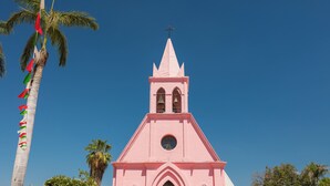 A pink church with a bell tower, palm trees, and flags. - Holiday Inn Express & Suites Ciudad Obregon by IHG (Cajeme)