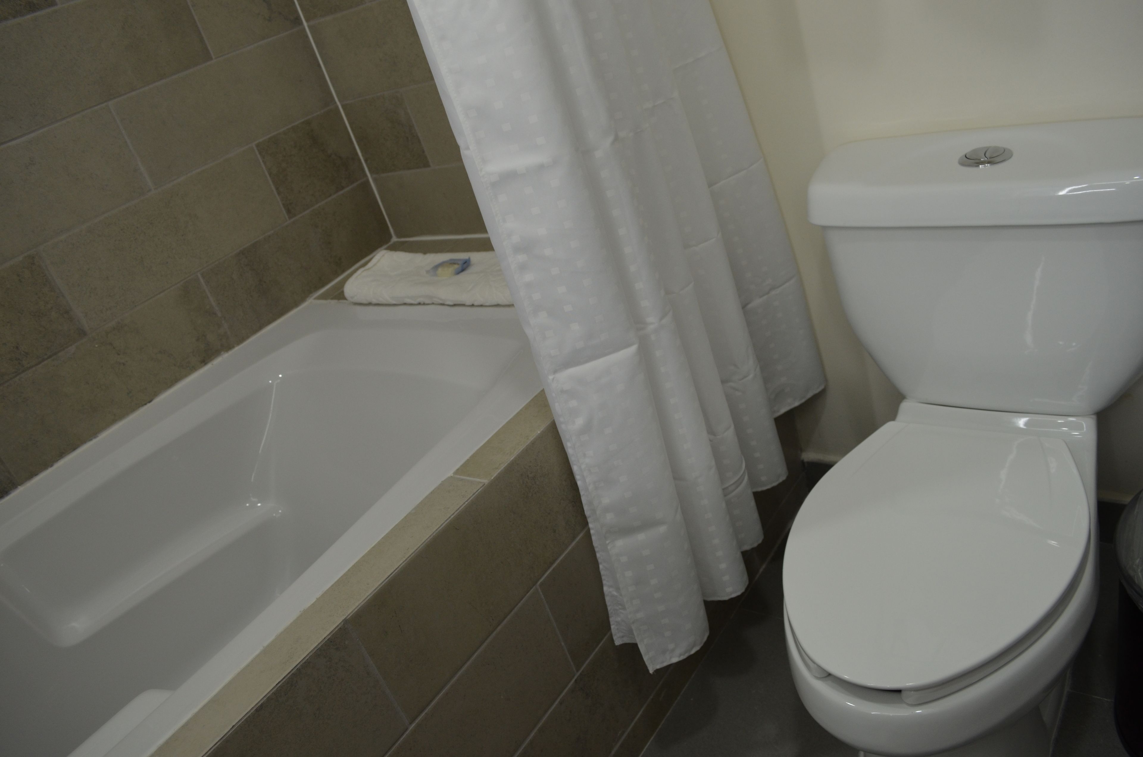 A bathroom with a bathtub, toilet, and shower curtain.