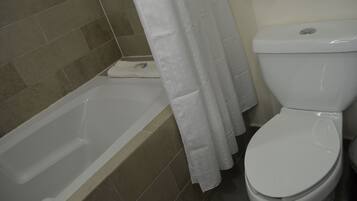 A bathroom with a bathtub, toilet, and shower curtain.