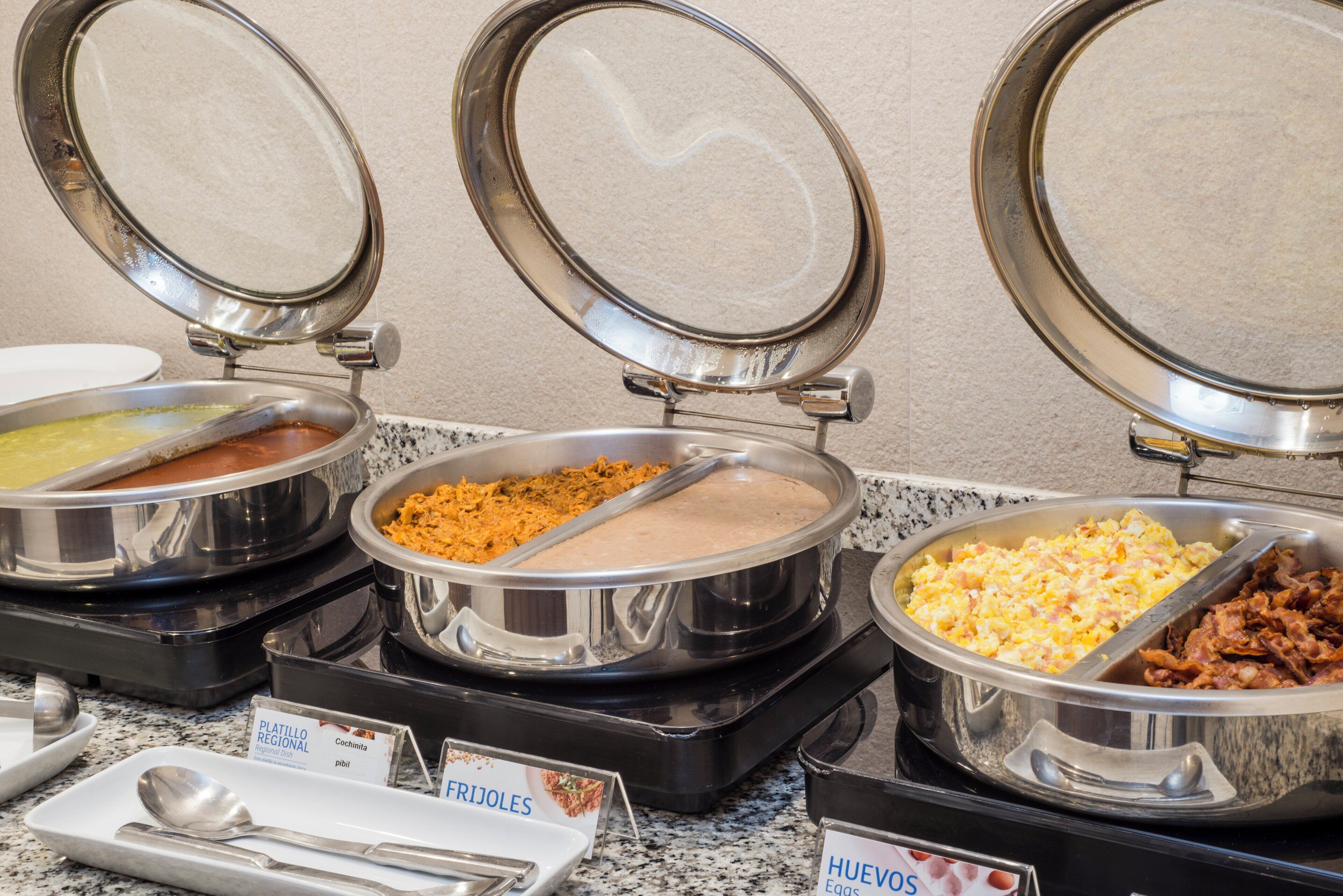 A buffet with labeled dishes including 'FRIJOLES' and 'HUEVOS'.