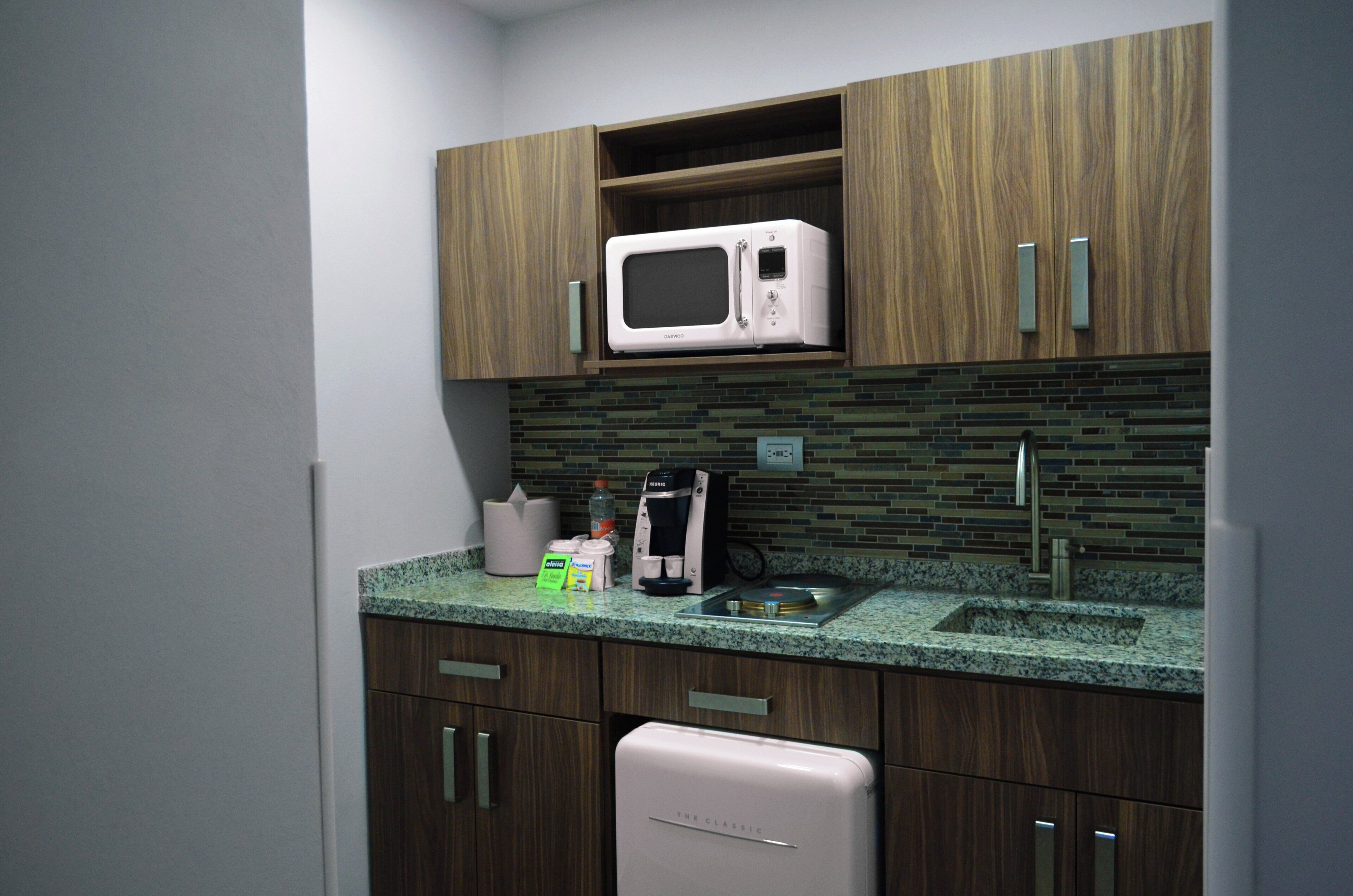 A kitchen with wooden cabinets, a microwave, a coffee maker, and a sink.