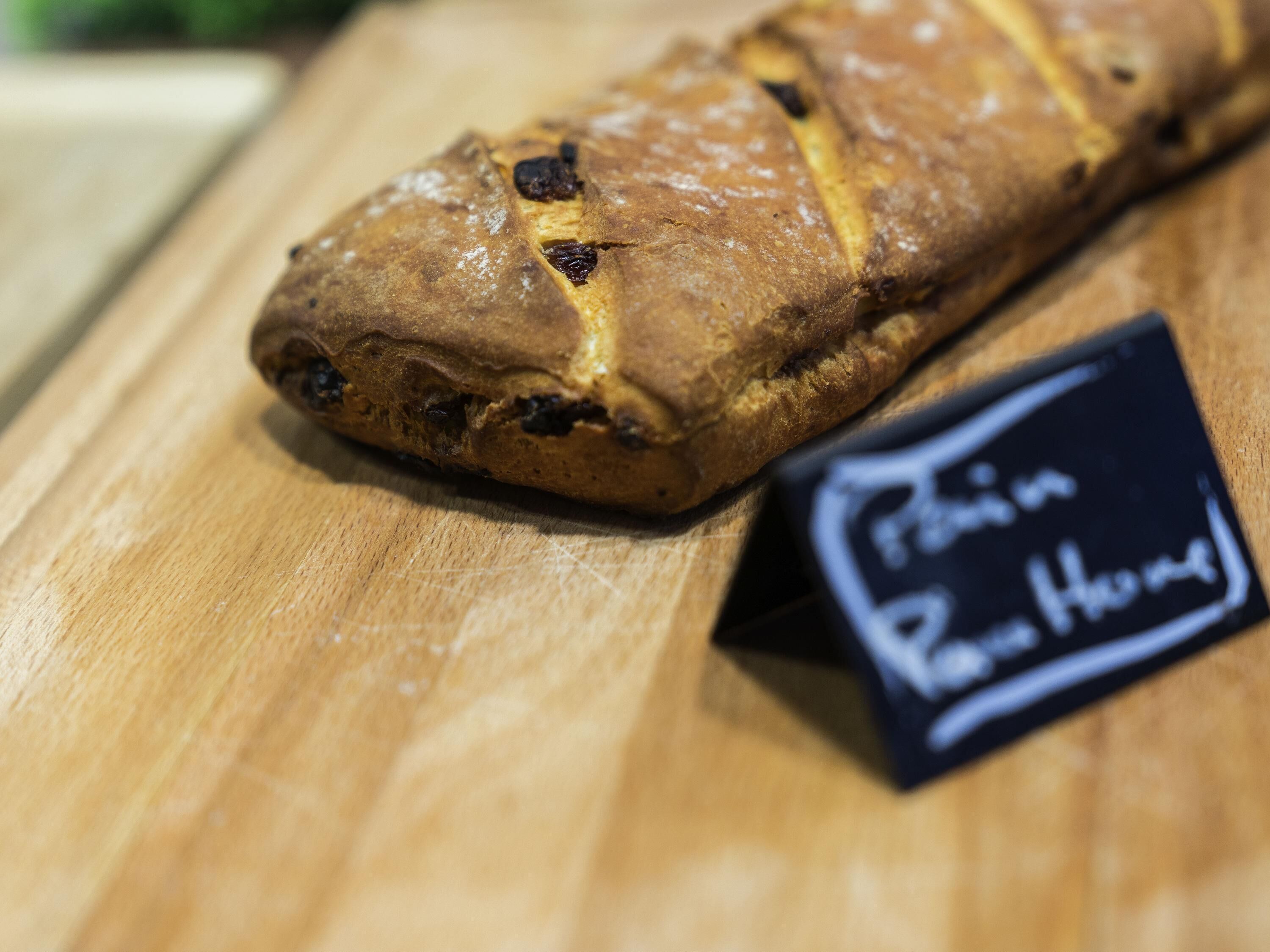 A loaf of bread on a wooden surface with a sign indicating it is a 'Pão de Rolo.'