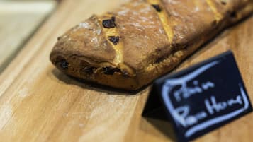 A loaf of bread on a wooden surface with a sign indicating it is a 'Pão de Rolo.'