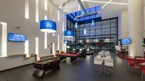 A modern indoor recreational area with pool tables, foosball, and bar seating.