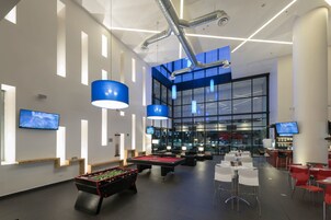 Un espacio recreativo interior moderno con mesas de billar, futbolín y asientos de bar.