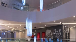 A modern interior with a glass staircase, a reception desk, and a unique ceiling light fixture.