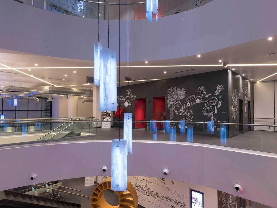 Un interior moderno con una escalera de cristal, una recepción y una lámpara de techo original.