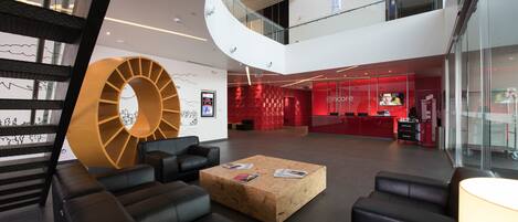 A modern lobby with black leather sofas, a wooden coffee table, and a large circular wall decoration.