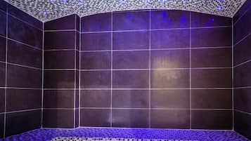 Bathroom features a sleek design with large tiles, a unique mosaic ceiling, and patterned floor.