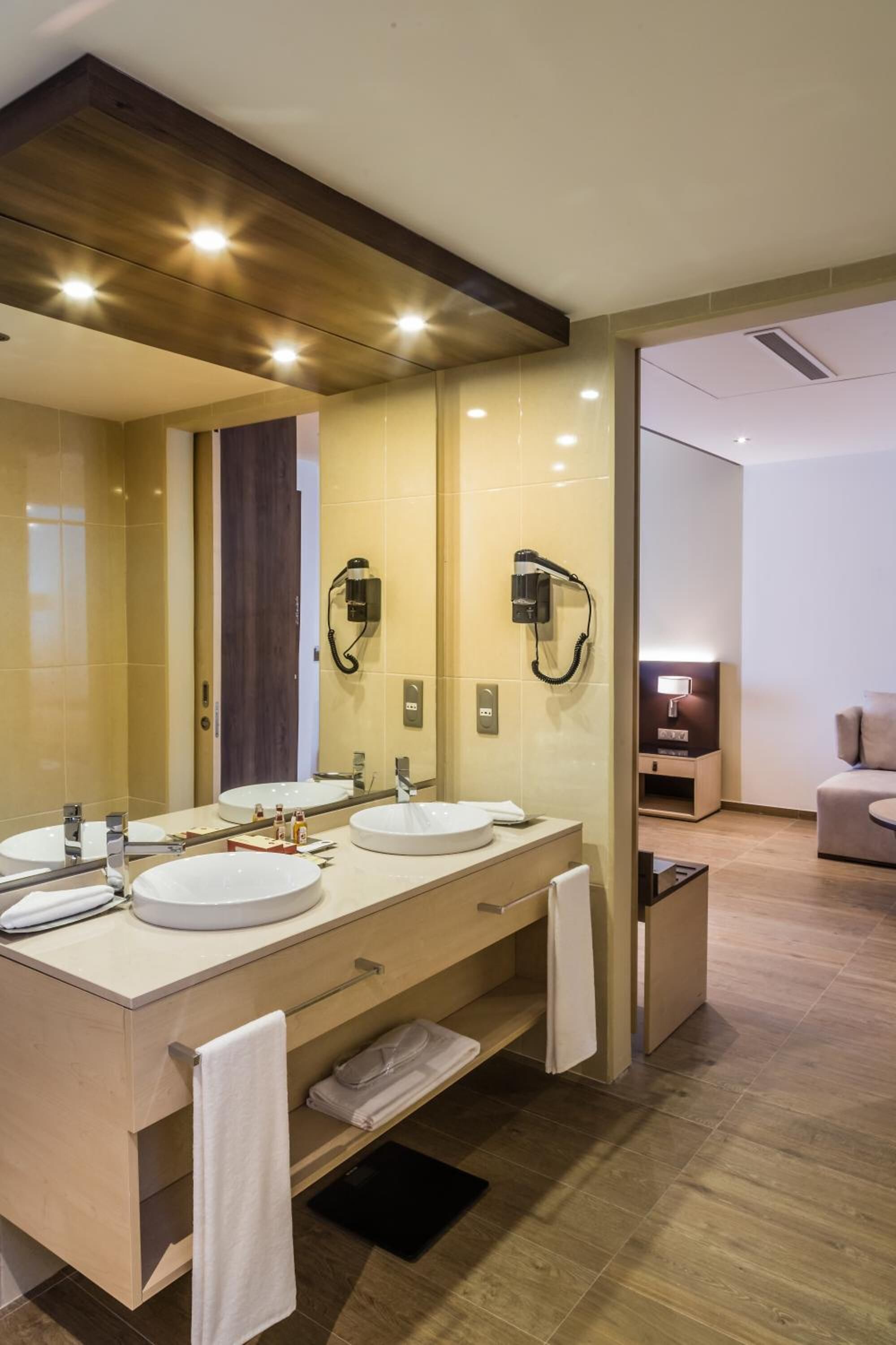 A modern bathroom with two sinks, a large mirror, and a hairdryer.