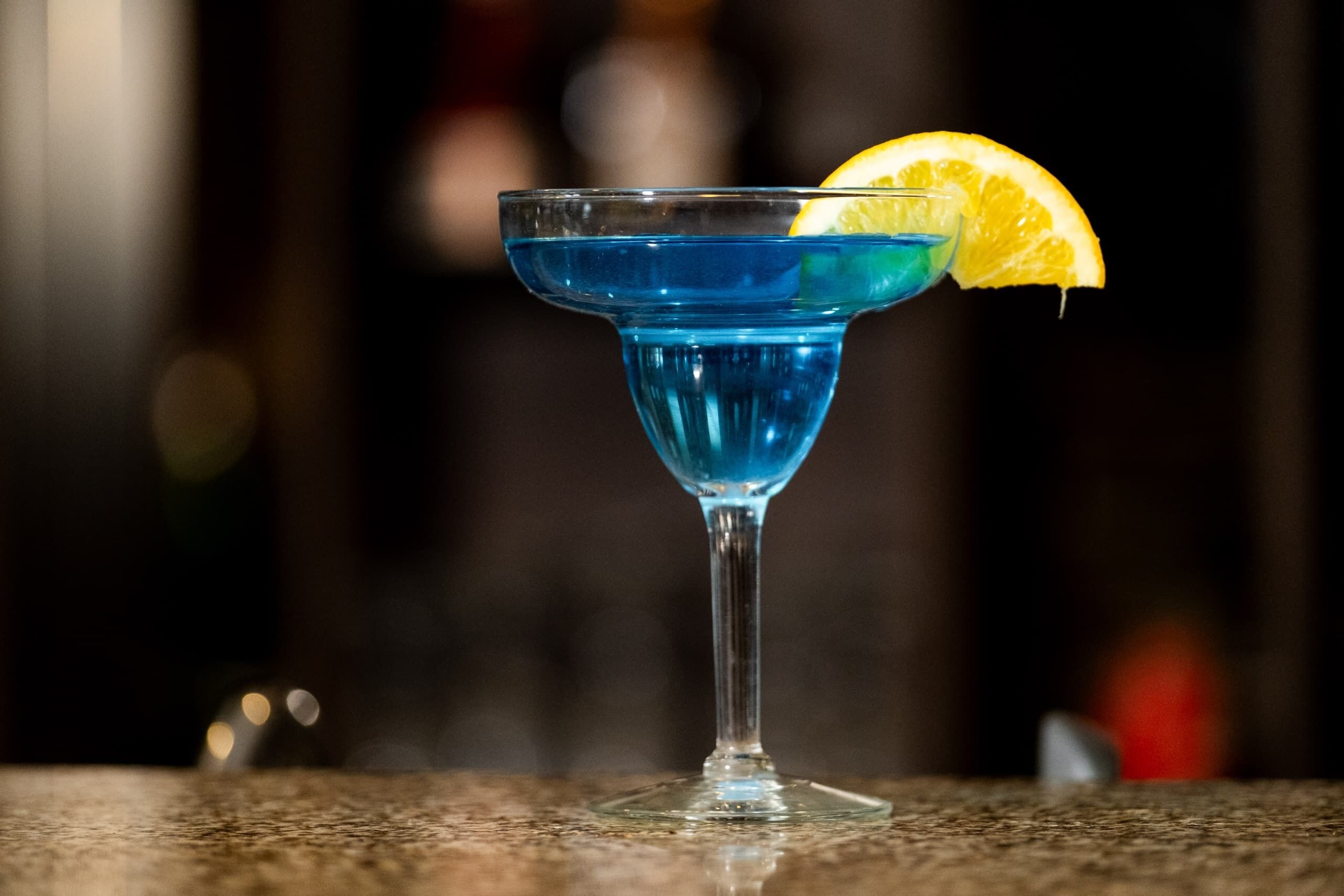 Un cocktail in un bicchiere da martini, guarnito con una fetta di limone.