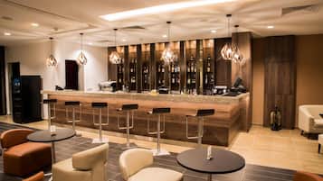 Un espace bar moderne doté d’un long comptoir, de nombreux tabourets et d’une grande variété de bouteilles.